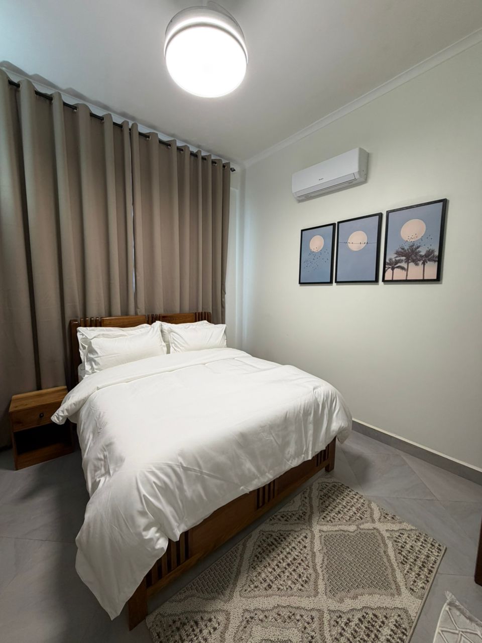 Double Hill Apartments cozy master bedroom with wooden bed, white bedding and air conditioning